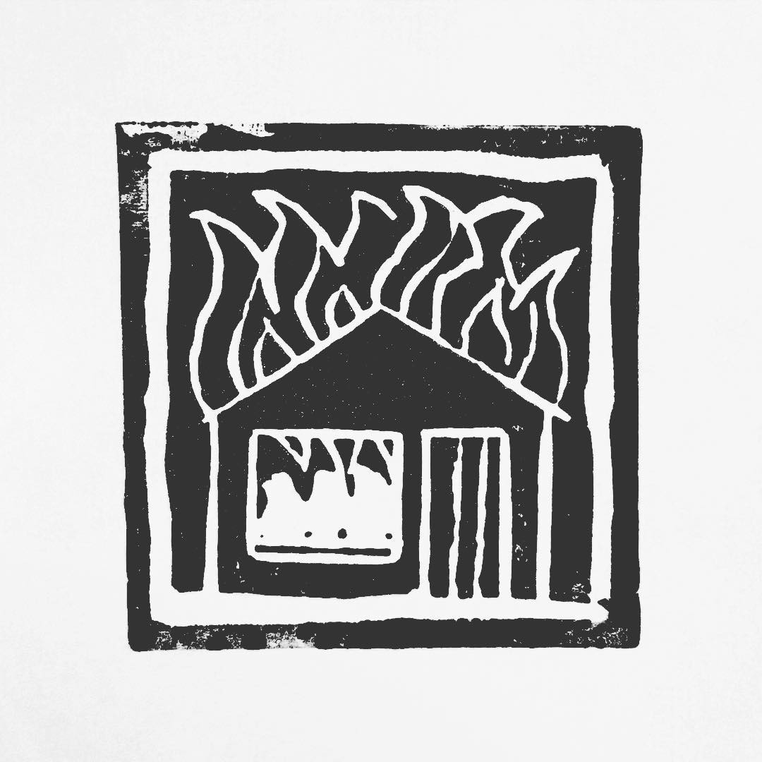 Lino print: a small house with flames rising from the roof and light in the window