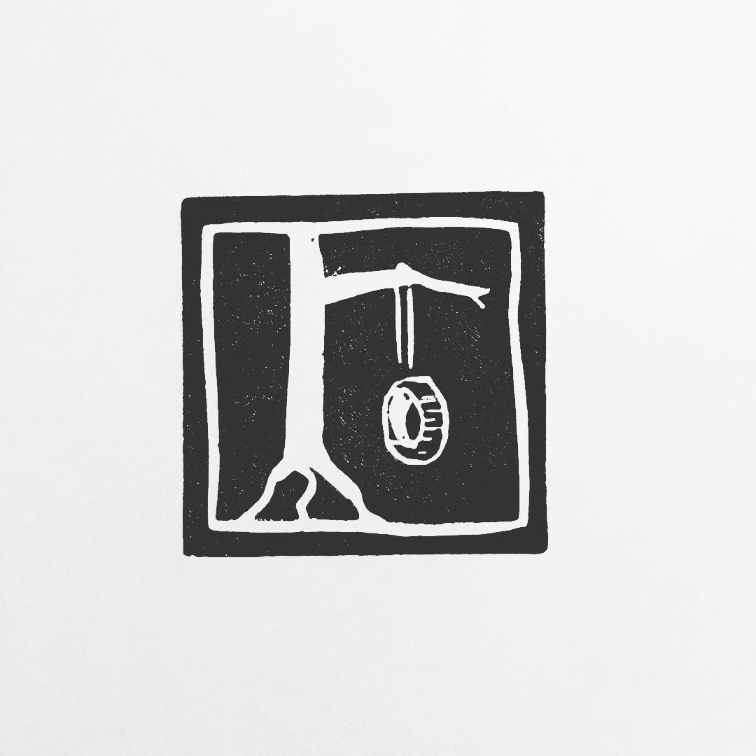 Lino print: a tyre swing hanging on a rope from the branch of a tree