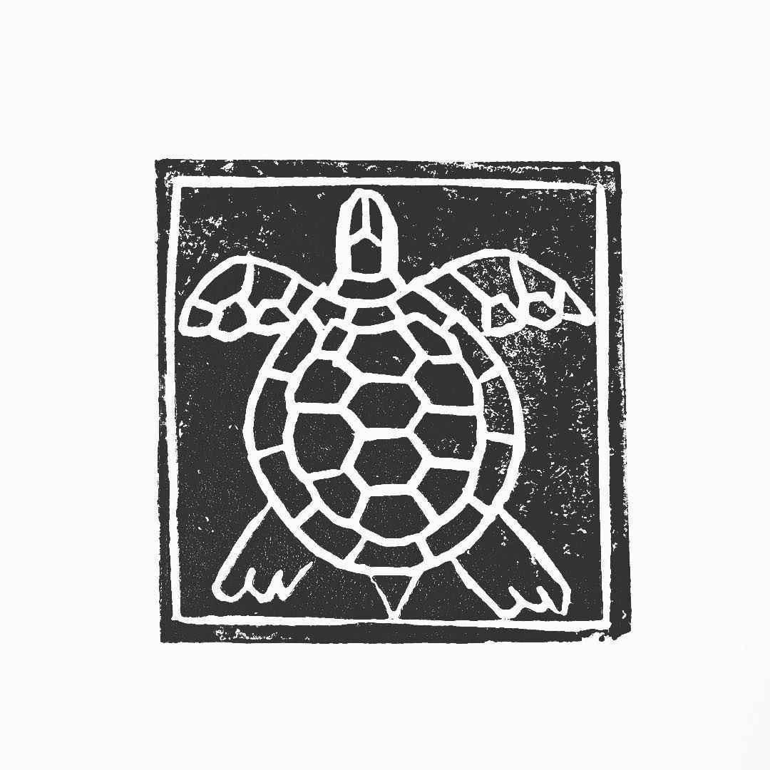 Lino print: a sea turtle seen from above, patterned shell and outstretched flippers
