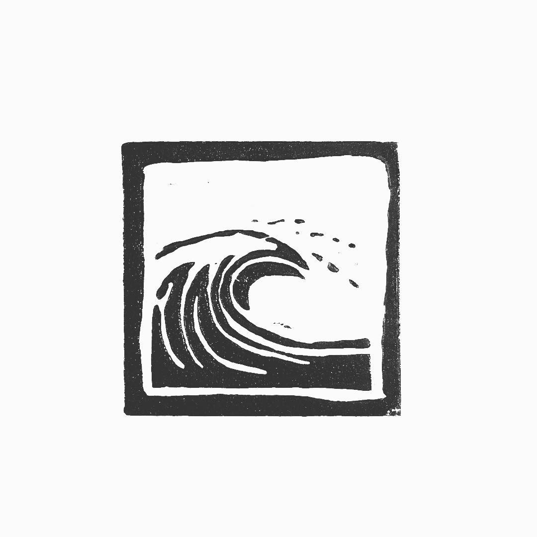 Lino print: a breaking wave curling over, spray flicking off the crest