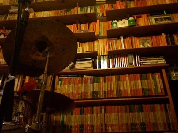 A cymbal and microphone set up in front of shelves of Penguin paperbacks